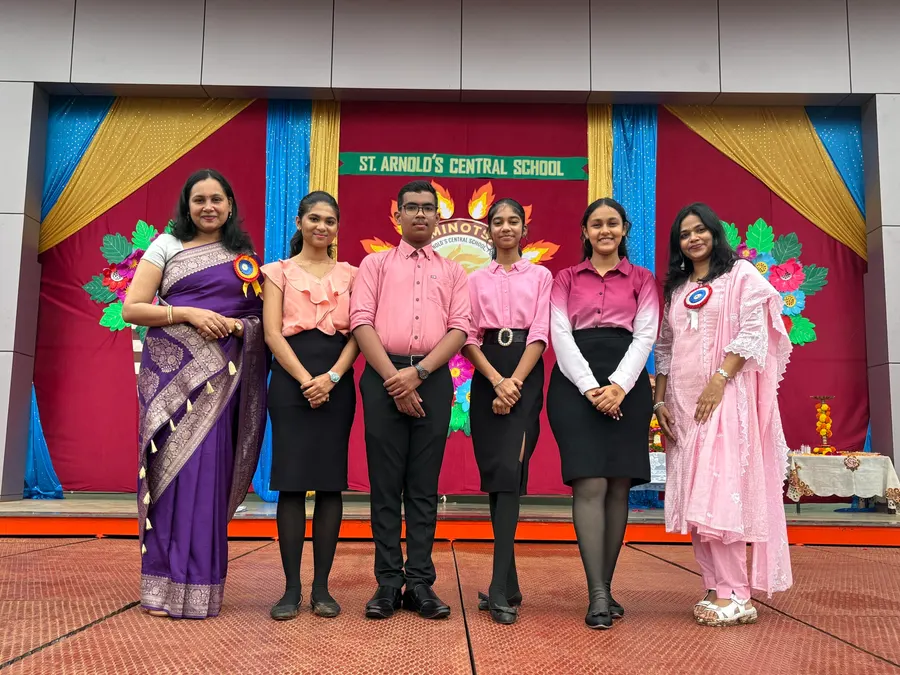 Students in traditional attire performing on stage with the school banner behind
